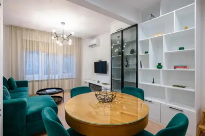 a living room with a wooden table and green chairs at Sunny Stylish Apartment in Sofia by Flat Mаnager in Sofia