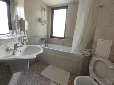 a bathroom with a tub and a sink and a toilet at Fenix Emerald in Bansko