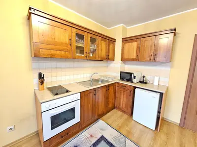 a kitchen with wooden cabinets and a white appliance at Two charming Studios in Trinity Bansko with balcony and free parking by Flat Mаnager in Bansko