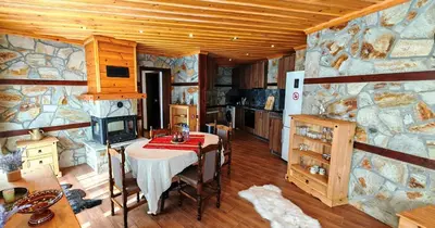 a dining room with a table and a stone wall at Rhodopski Apartment in Chepelare