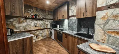 a kitchen with wooden cabinets and a stone wall at Rhodopski Apartment in Chepelare