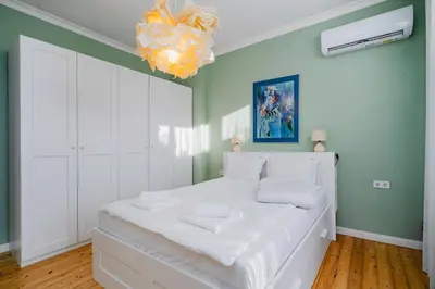 a white bed in a room with a chandelier at Charming 1BD Apartment Next to Women's Market by Flat Mаnager in Sofia