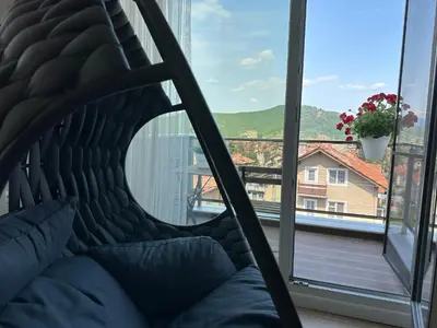 a couch in front of a window with a view at Апартамент с люлка и гледка в The House с Термална зона in Velingrad