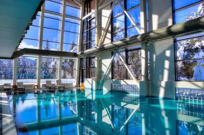 a large swimming pool with blue water and windows at Alpine Charm Borovets Apart in Borovets