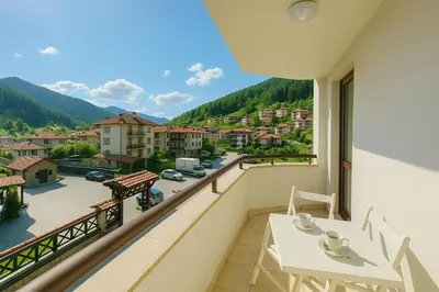 a balcony with a table and a view of a city at Апартамент и Студио Перелик in Chepelare