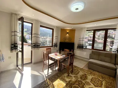 a living room with a table and a couch at Апартамент и Студио Перелик in Chepelare