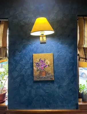 a blue wall with a lamp and a picture of flowers at Hotel MERIDA in Blagoevgrad