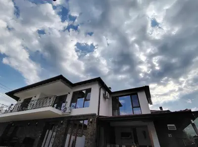 a house with a cloudy sky in the background at Вила Анжелика in Ilinden