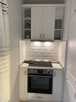 a small kitchen with a stove and white cabinets at Blavka apartment Gardenia in Sofia