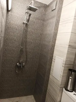 a shower in a bathroom with a tile wall at Апартамент тип хотелска стая in Plovdiv