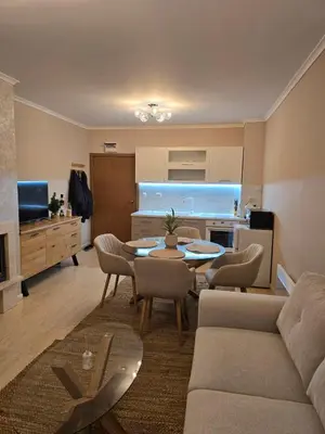 a living room with a table and chairs and a kitchen at Костадинов 2 in Pamporovo