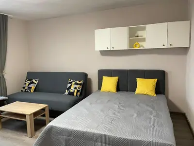 a bedroom with a bed and a couch with yellow pillows at Magnolia city view studio in Sofia