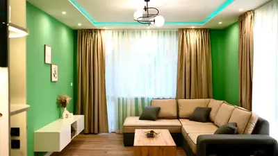 a living room with a couch and a green wall at Downtown Gem in Plovdiv