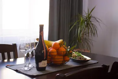a bottle of wine and a bowl of fruit on a table at Serenity Apartment Bansko in Bansko
