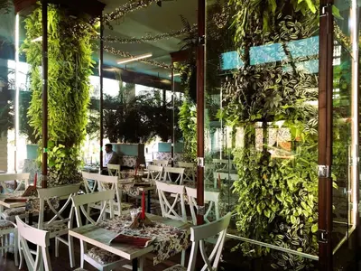 a restaurant with tables and chairs and plants on the wall at Sirius Apartment in Sofia