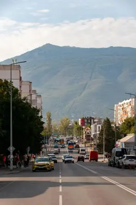 a city street with cars driving down a street with a mountain at Sirius Apartment in Sofia