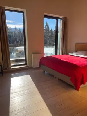 a bedroom with a red bed and a large window at Maisonette Mountain View - Euphoria Resort in Borovets