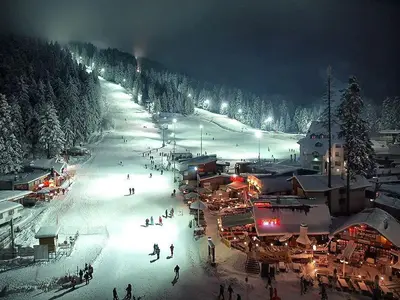 a group of people skiing down a ski slope at night at Maisonette Mountain View - Euphoria Resort in Borovets