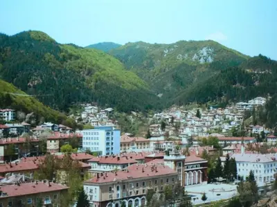 a group of buildings on a hill with mountains at Хотелски комплекс Релакс in Rudozem