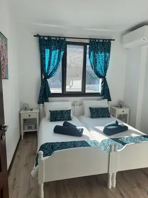 two beds in a bedroom with blue curtains at Апартамент Слънчев дом in Smolyan