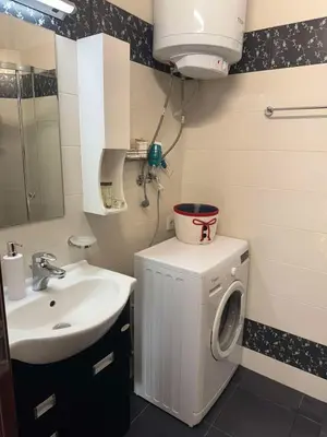 a bathroom with a washing machine and a sink at Апартамент Слънчев дом in Smolyan