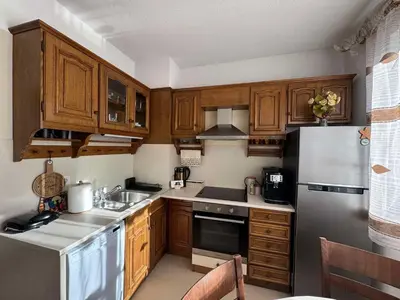 a kitchen with wooden cabinets and stainless steel appliances at Апартамент Слънчев дом in Smolyan