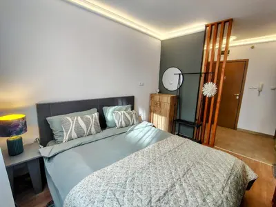 a bedroom with a large bed and a mirror at Ski lift studio in Bansko