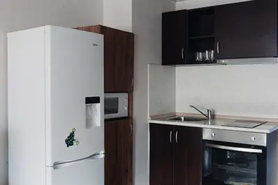 a kitchen with a white refrigerator and wooden cabinets at Pirin Peaks Residence - next to Ski Lift in Bansko