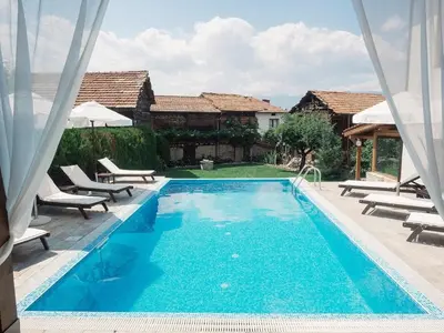 a blue swimming pool with chairs and a house at Villa Leventy in Banya