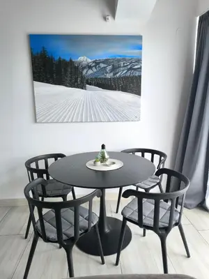 a table and chairs in a room with a picture on the wall at FEDORA - Luxury Penthouse in Pirin Golf & SPA in Razlog
