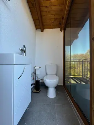 a bathroom with a toilet and a balcony at Вила Mountain Ship in Dedovo