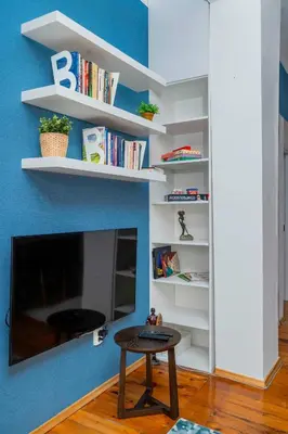 a living room with a table and a tv and shelves at Cozy and Central 2BD Flat - At the Heart of It All by Flat Mаnager in Sofia