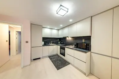 a kitchen with white cabinets and black appliances at Апартамент за гости Райково in Smolyan