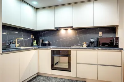 a kitchen with white cabinets and a microwave at Апартамент за гости Райково in Smolyan