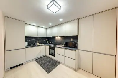 an empty kitchen with white cabinets and appliances at Апартамент за гости Райково in Smolyan
