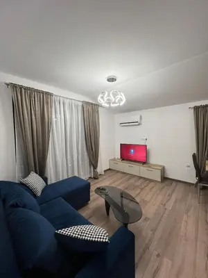 a living room with a blue couch and a tv at Atayana Apartment in Sofia