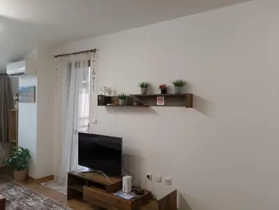 a living room with a flat screen tv on a wall at Двустаен апартамент 