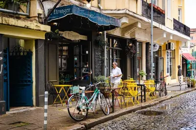 a man standing in front of a cafe with a bike at Center Stay Stylish 2BR near Serdika Metro in Sofia