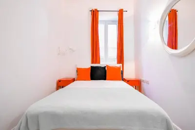 a bedroom with a bed with orange curtains and a mirror at Center Stay Stylish 2BR near Serdika Metro in Sofia