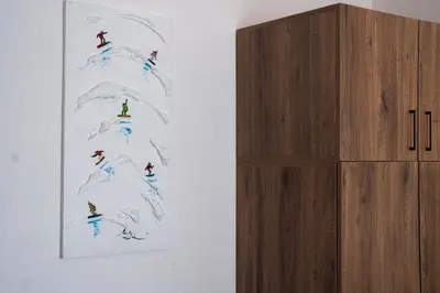 a wall with a painting of people riding a wave at Host2U Highland Hideaway Bansko in Bansko