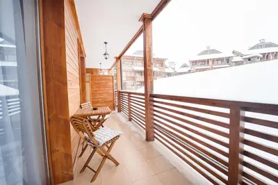 a balcony with a table and a chair on it at Host2U Highland Hideaway Bansko in Bansko
