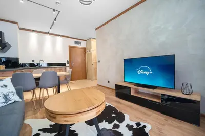 a living room with a large tv and a table at Host2U Highland Hideaway Bansko in Bansko