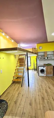 a living room with yellow walls and stairs in a house at Tranquility Lodge, next to Paradise and metro station in Sofia