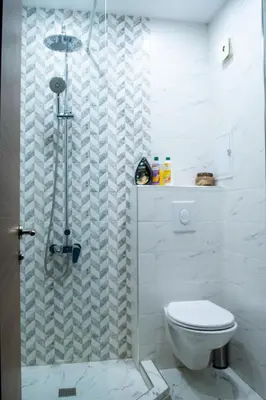 a white bathroom with a shower and a toilet at HD Comfort Apartment in Sofia