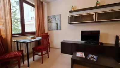 a living room with a small table and a television at Borovets Gardens Aparthotel Seasons Borovets PM in Borovets