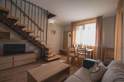 a living room with a couch and a staircase at Borovets Gardens Aparthotel Seasons Borovets PM in Borovets