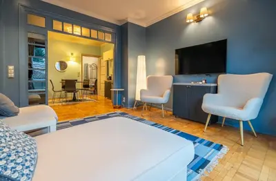 a living room with a bed and a tv and chairs at Stylish 2 BDRM Apt at NDK in Sofia