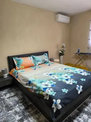 a bed with a blue blanket with flowers on it at Апартамент Котеви in Sandanski