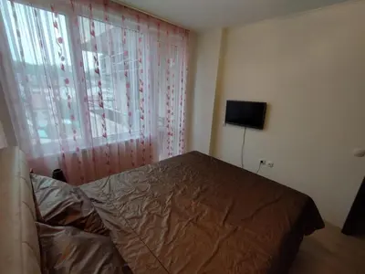 a bedroom with a bed and a window with a television at Апартамент Сандански Център in Sandanski