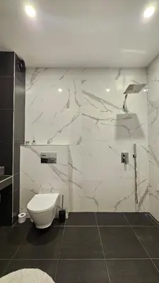 a bathroom with a toilet and a marble wall at Cozy Urban Heaven with Dedicated Parking Spot in Sofia